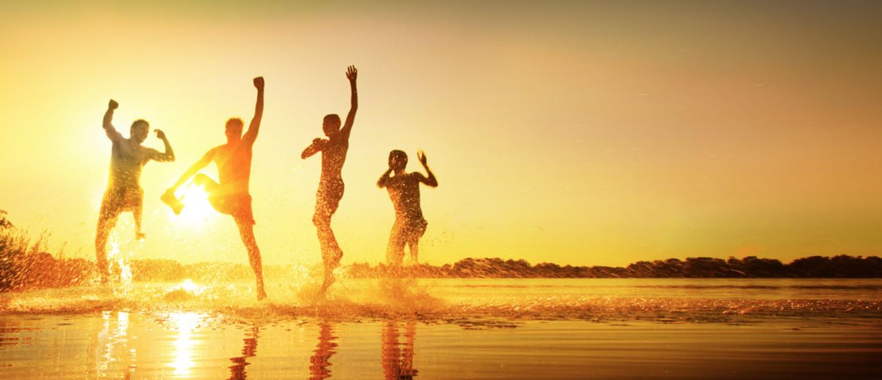 Tanzende Menschen am Meer feiern ihr glückliches Leben